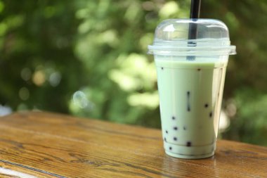 Tahta masada plastik bardakta lezzetli sütlü çay. Metin için boşluk