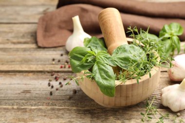 Kabuklu havan, ahşap masada farklı aromatik otlar ve baharatlar, yakın plan. Metin için boşluk