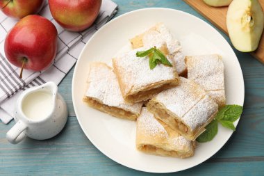 Lezzetli elmalı turta parçaları pudra şekeri, nane ve açık mavi ahşap masa üzerinde meyveler, düz yatıyordu.