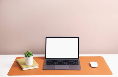 İçerideki beyaz masada dizüstü bilgisayarı ve turuncu faresi olan şık bir iş yeri. Metin için boşluk