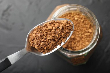 Koyu dokulu masa üzerinde granüle hazır kahve ve kavanoz, üst manzara.