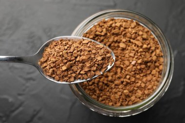 Koyu dokulu masa üzerinde granüle hazır kahve ve kavanoz, üst manzara.