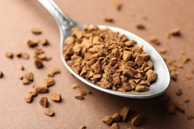 Bej arka planda granülatif hazır kahve kaşığı, yakın plan.