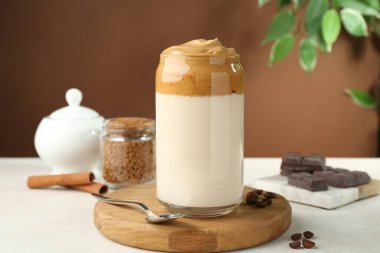 Bardakta lezzetli dalgona kahvesi, fasulye, granül, çikolata ve tarçın beyaz masada.