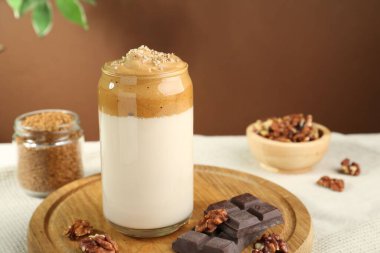 Bardakta lezzetli dalgona kahvesi, çikolata parçaları, ceviz ve granüller masada, yakın plan.