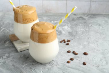 Bardakta lezzetli dalgona kahvesi ve gri masada fasulye, yakın plan. Metin için boşluk