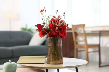 Vazoda güzel gelincik çiçekleri ve evdeki ahşap masada kitap.