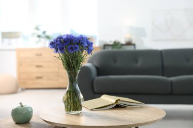 Vazodaki güzel mavi çiçek ve evdeki ahşap masada kitap. Metin için boşluk