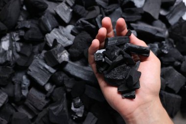 Yığının üzerinde siyah kömürleri olan adam, manzaranın üstünde