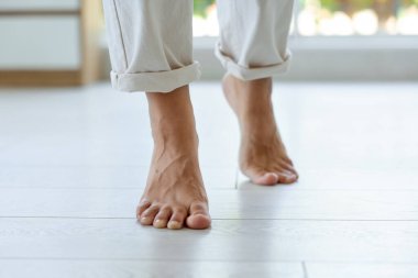 Kadın sıcak zeminde yürüyor, yakın plan. Isıtma sistemi