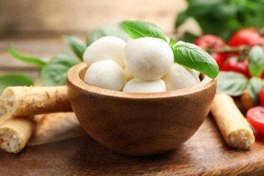 Lezzetli mozzarella peynir topları, domatesler, fesleğen ve Grissini masada, yakın plan.