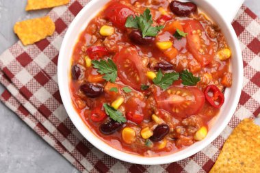 Lezzetli biberli makarna kasede ve nachos gri desenli masada, düz yerde.