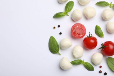Lezzetli mozzarella peyniri topları, domatesler, fesleğen ve beyaz arka planda biberler, düz yatak. Metin için boşluk