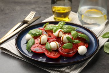 Caprese salatası. Gri masadaki balzamik sirkeyle servis ediliyor. Yakın plan.