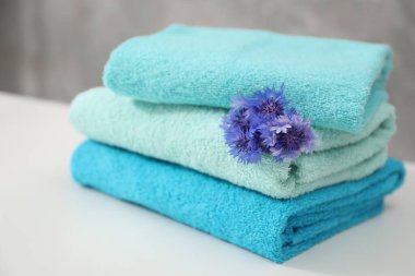 Beyaz masada renkli havlu ve çiçekler yığını, yakın plan.