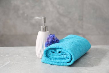 Gri mermer masada yumuşak havlu, çiçekler ve sıvı sabun.