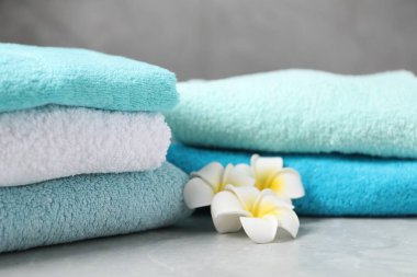 Yumuşak havlu yığınları ve gri mermer masa üzerindeki tesisat çiçekleri, yakın plan.