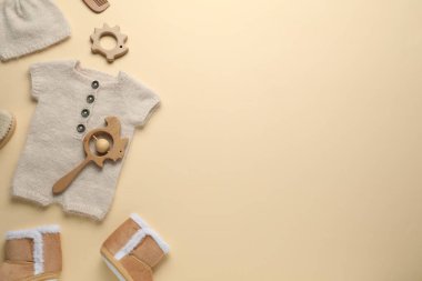 Bej arka planda bebek kıyafetleri ve aksesuarlar, düz yatış. Metin için boşluk