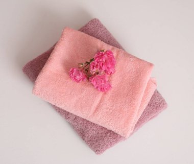 Renkli havlu yığını ve çiçekler beyaz masada, üst görünümde.