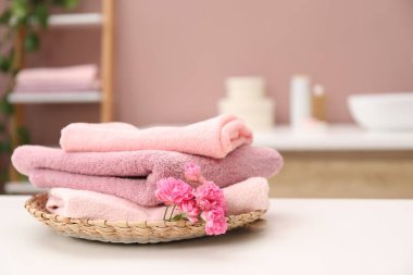 Banyodaki beyaz masada renkli havlular ve çiçekler, yakın plan. Metin için boşluk