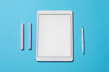Tablet ve açık mavi zemin üzerinde farklı kırtasiye malzemesi, düz yatıyordu