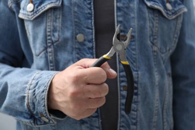 Kapalı mekanda pense giyen adamın yakın görüntüsü.