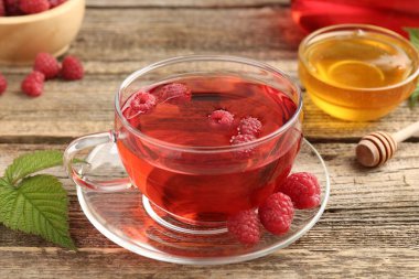 Lezzetli ahududu çayı, böğürtlen ve yapraklar ahşap masada, yakın plan.