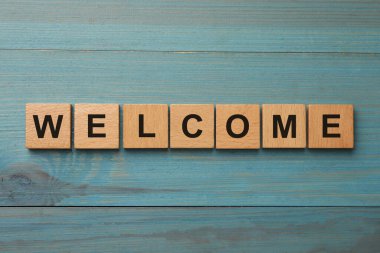 Kelime. Açık mavi masadaki ahşap küplerden yapılmış hoş geldiniz.
