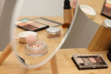 Farklı makyaj ürünleri ve kapalı mekanlarda makyaj aynası, yakın çekim.