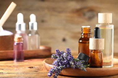 Ahşap masa üzerinde lavanta yağı ve çiçek şişeleri, yakın plan. Metin için boşluk