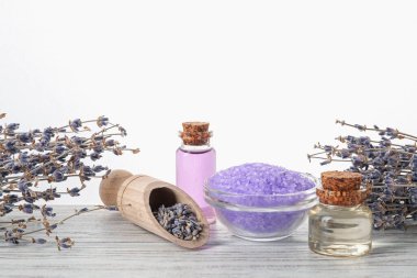 Doğal gaz, deniz tuzu ve lavanta çiçekleri ahşap masada beyaz arka planda.