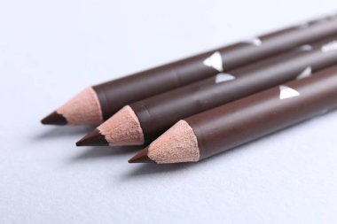 Beyaz arka planda üç kaş kalemi, yakın plan.