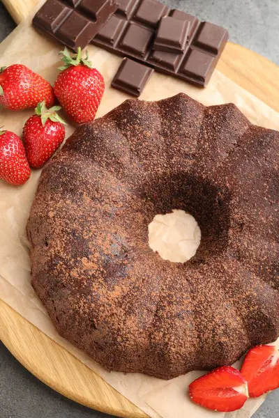 Lezzetli kek, çikolata parçaları ve gri masadaki çilekler, düz konum