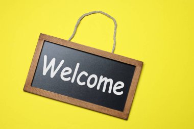 Sözcüklü küçük tahta Sarı arka planda hoş geldiniz, üst görünüm