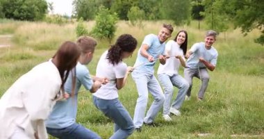 Takım oluşturma. Dışarıda halatla çekme oyunu oynayan bir grup mutlu insan.