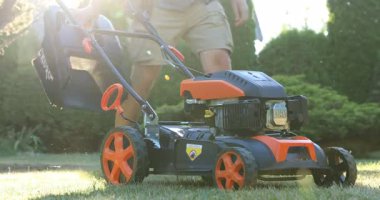 Lviv, Ukrayna - 2 Temmuz 2025: Bahçedeki çim biçme makinesine çim biçme makinesi takan adam, yakın plan