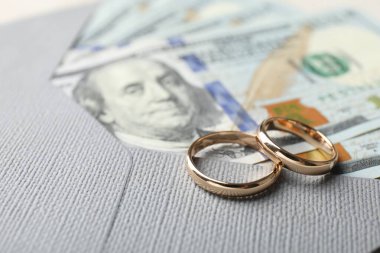 İki altın alyans, dolar banknotları ve zarf, yakın plan.