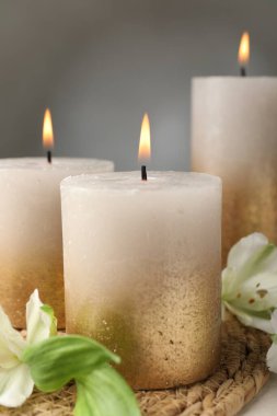 Yanan mumlar ve zambak çiçekleri masada, yakın plan.