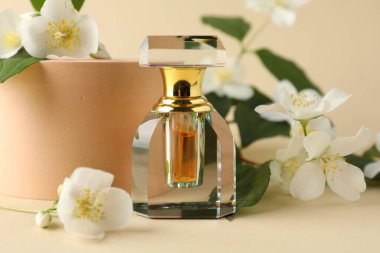 Bir şişe parfüm ve bej arka planda yasemin çiçekleri, yakın plan.