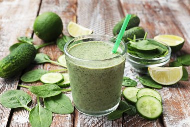 Lezzetli ıspanaklı smoothie ve ahşap masada malzemeler, yakın plan.