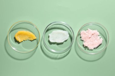 Petri kaplarında yeşil arka planda farklı kozmetik ürünleri var.