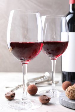 Kırmızı şarap ve yer mantarı şekerleri beyaz masada gri arka planda, yakın plan