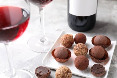 Bardakta kırmızı şarap ve hafif desenli masada yer mantarı şekerlemeleri, yakın plan.