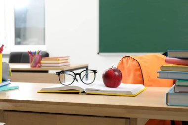 Farklı okul kırtasiyesi, gözlük ve kırmızı elma.