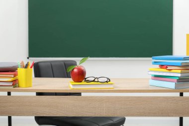 Farklı kırtasiye malzemeleri, gözlük ve kırmızı elma.