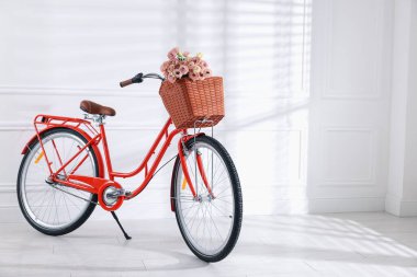 Beyaz duvarın yanında güzel çiçeklerle dolu bir bisiklet. Metin için boşluk