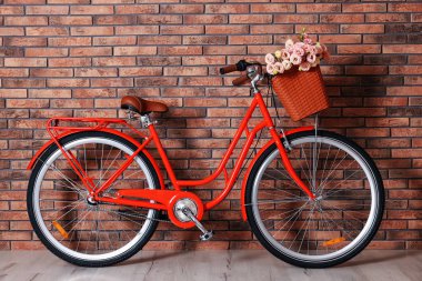 Evin içinde tuğla duvarın yanında bir sepet güzel çiçekli bisiklet.