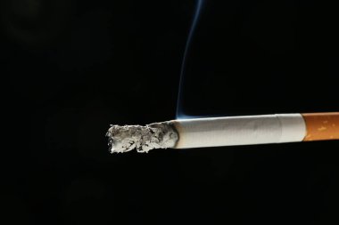 Siyah arka planda yanan bir sigara, yakın plan.