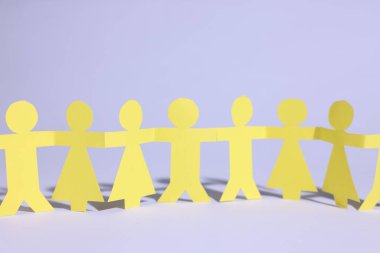 Beyaz arka planda el ele tutuşan insanların kağıt figürleri.