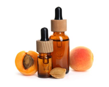 Beyaz üzerine izole edilmiş yağ şişeleri, taze kayısılar ve çekirdekler